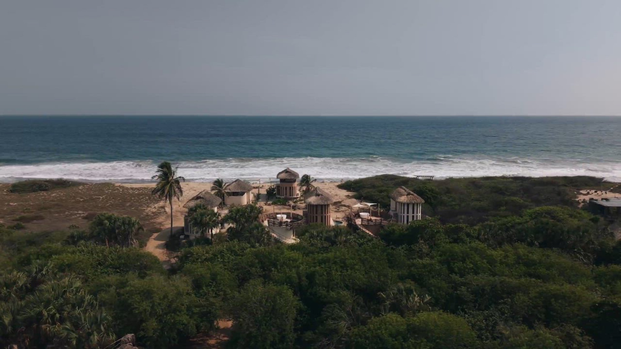 Casa Sal's thatched villas between the coastal forest and the Pacific, seen from the air